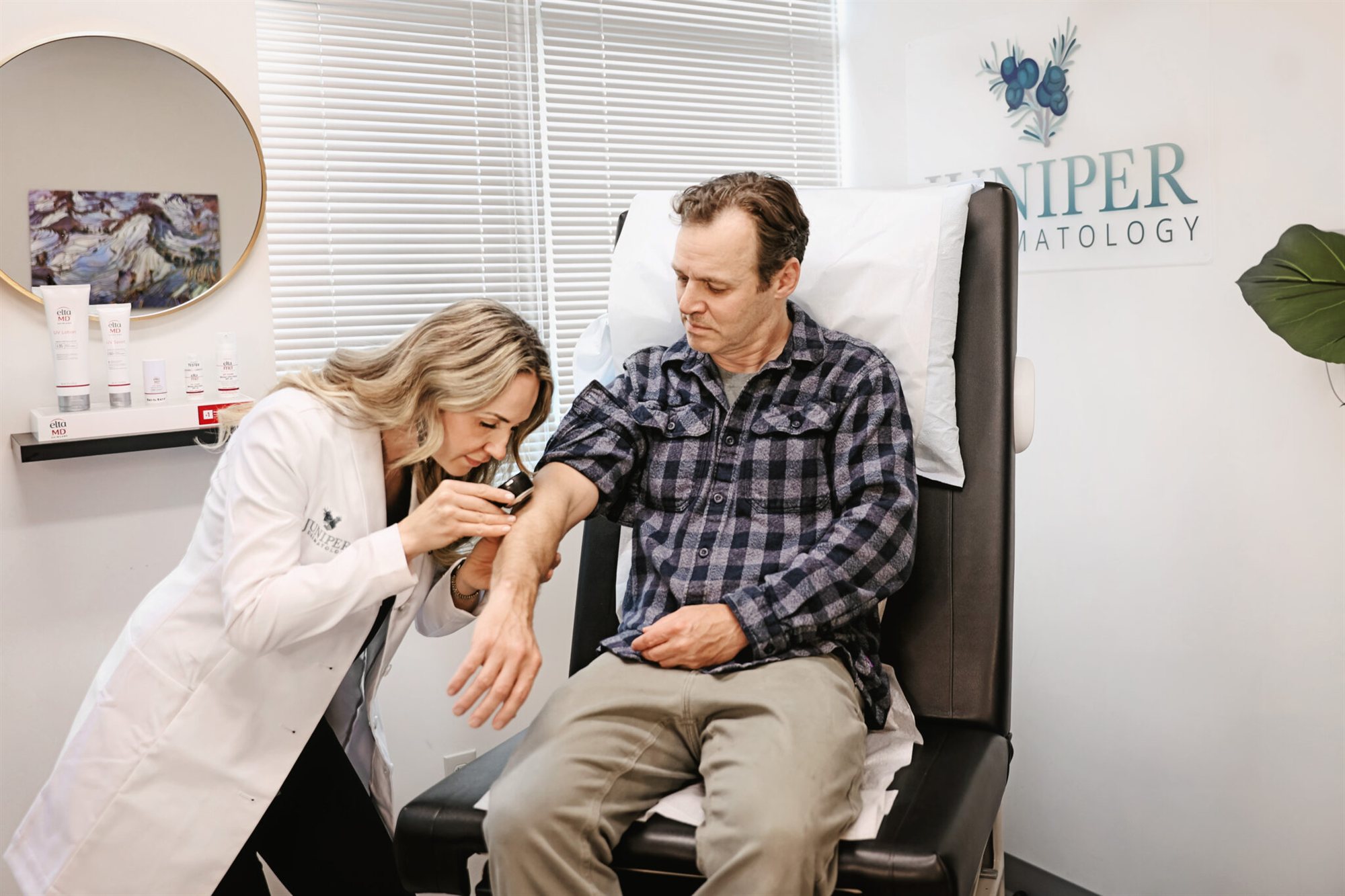 Dr. Karla Pivik examining an adult patient's arm for eczema at Juniper Dermatology