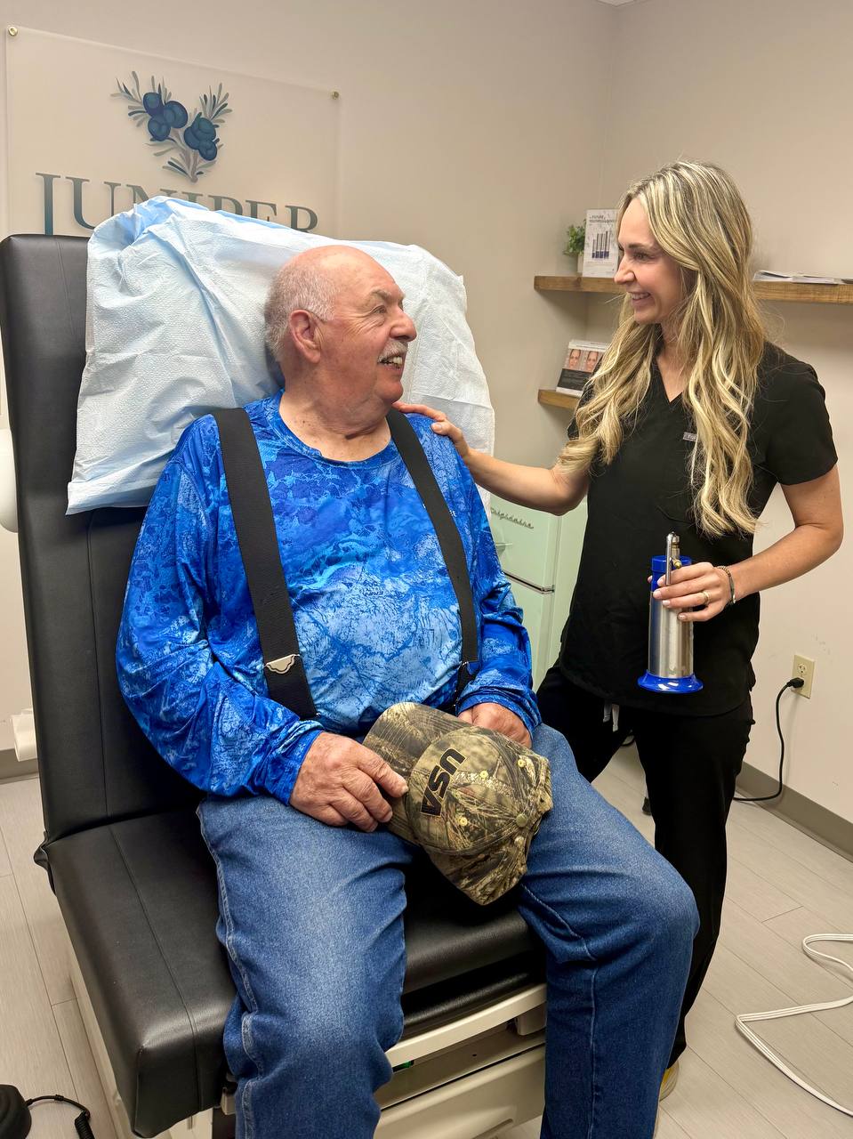 A Juniper Dermatology provider reassuring an older patient during skin cancer care in the exam room